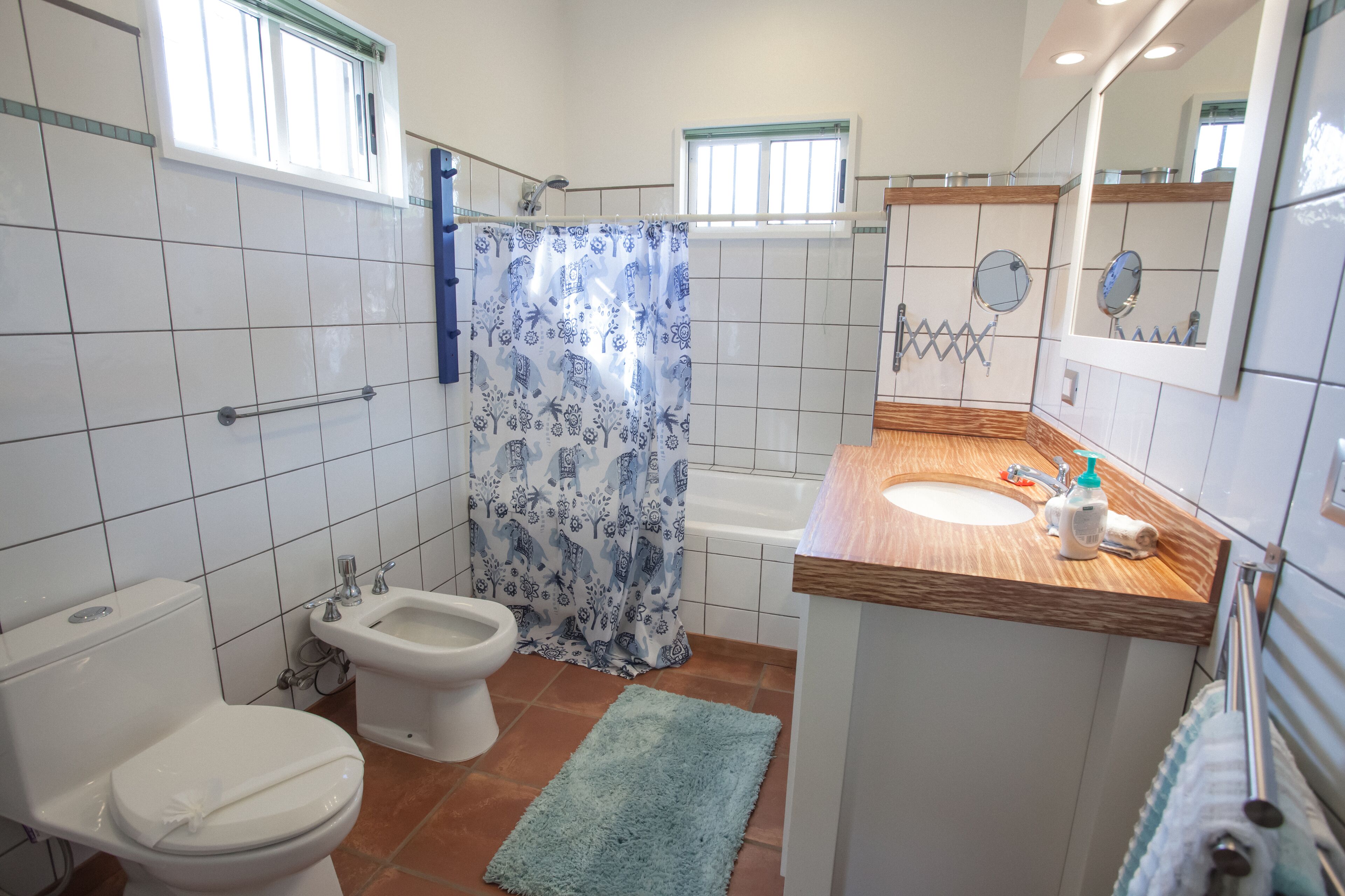 Un baño con inodoro, bidé, bañera y lavamanos con encimera de madera.