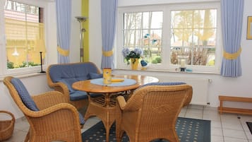 A room with wicker furniture, a round table, and a window with curtains.