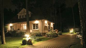 A two-story house with a paved driveway and well-lit exterior.