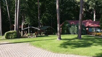 A lodge with a red-roofed cabin, a picnic area, and a paved walkway.