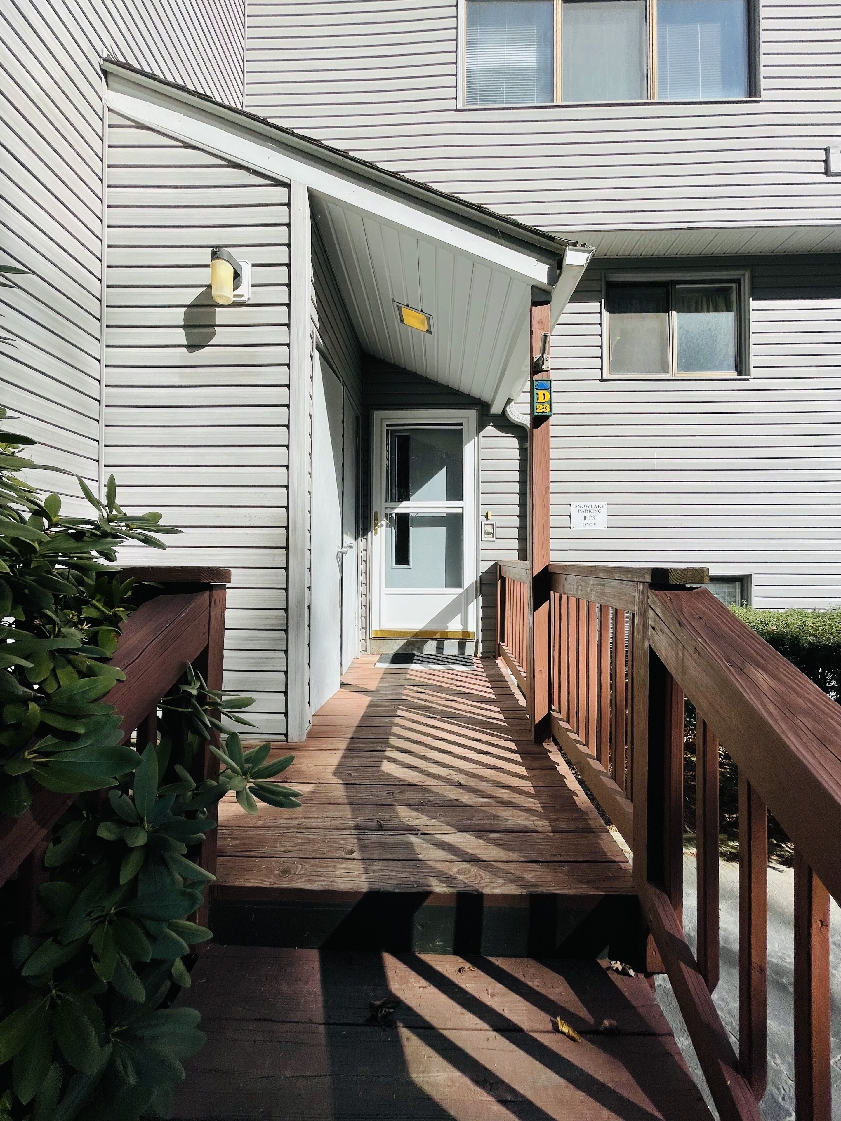 A wooden deck leading to a building entrance with a mailbox and a door.
