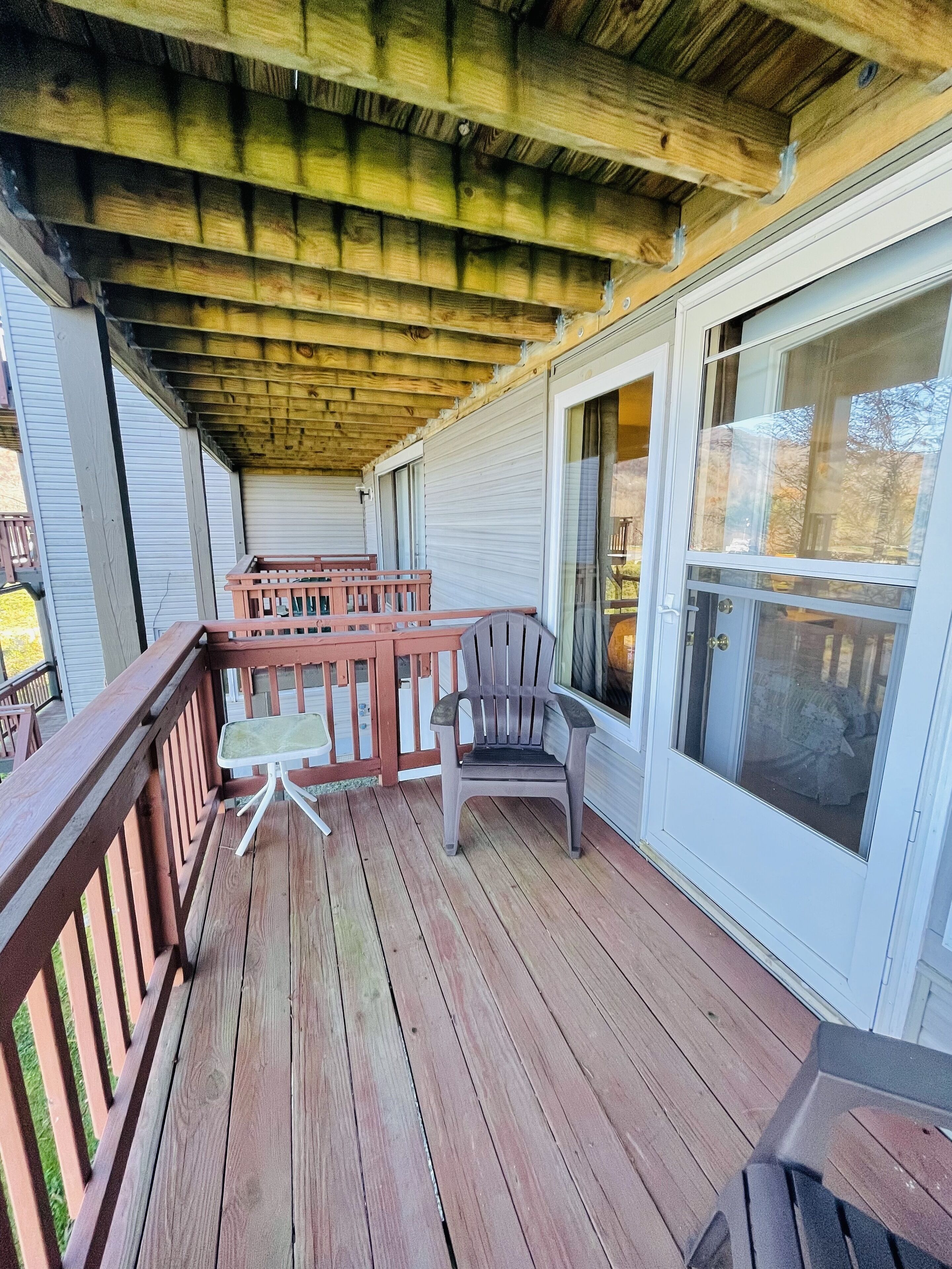 A wooden deck with a railing, a table, and two chairs.