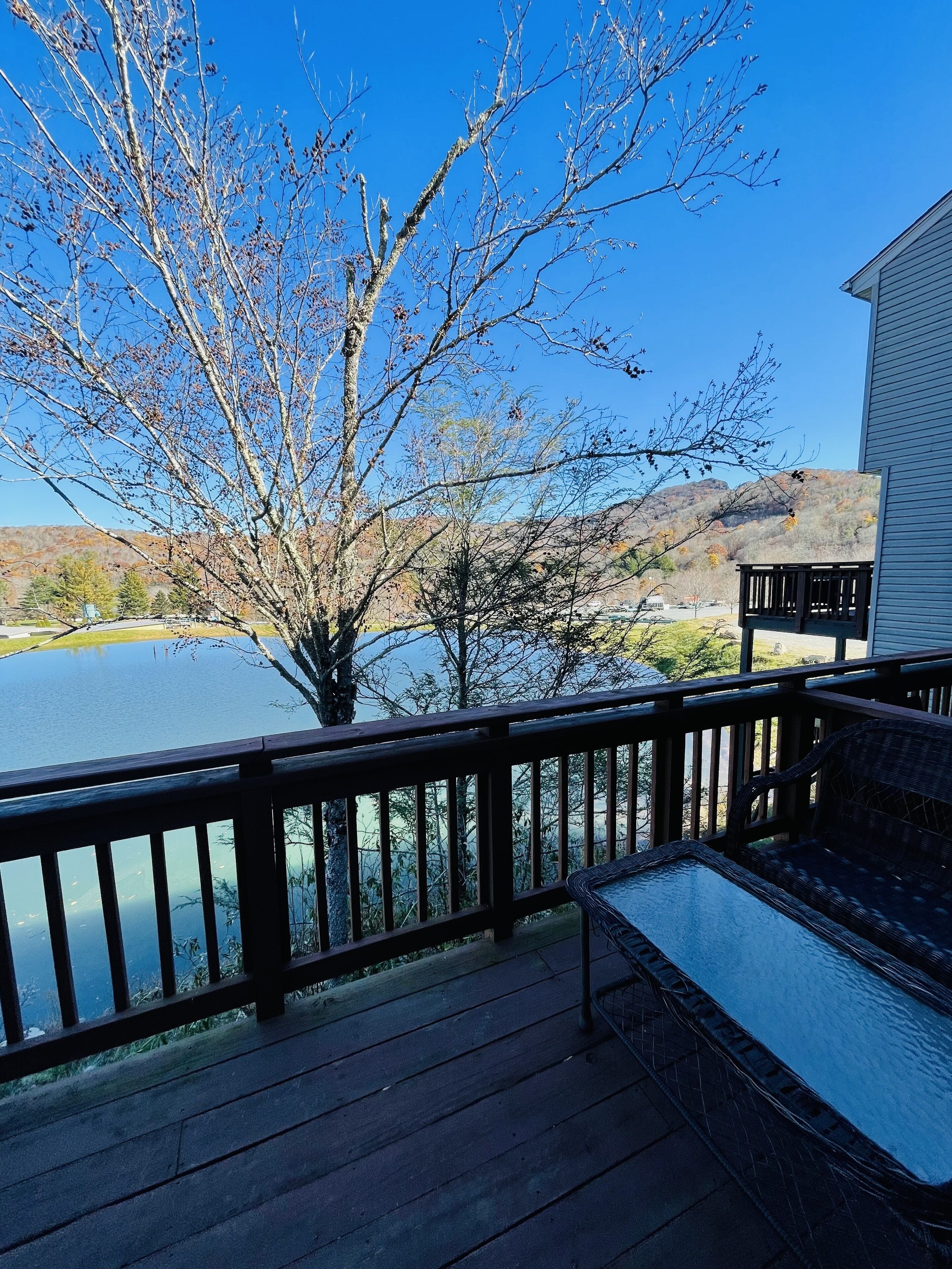 Une terrasse en bois offrant une vue sur un lac et des collines en arrière-plan.