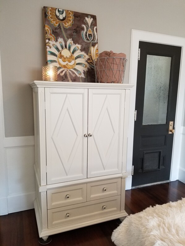 A white armoire with two doors, a small shelf, and three drawers.
