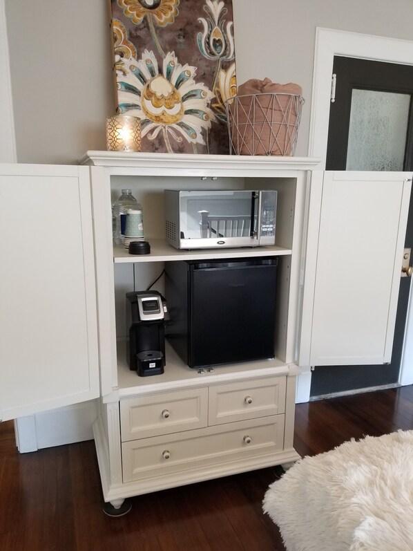 A white cabinet with a microwave, coffee maker, and a small refrigerator.