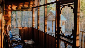 Une cabane en bois dotée de grandes fenêtres, d’un banc en bois et d’une petite table.