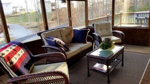 A covered outdoor seating area with wicker furniture, a cushioned sofa, and a small table with a plant. - Lake Cumberland Hideaway #1-2 miles from Jtown Marina! Boat Parking & Fire Pit! (Jamestown)