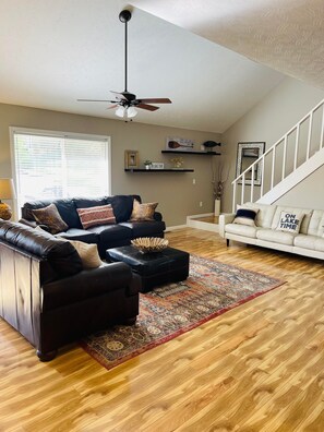 A living room with a dark leather sofa, a white sofa, a patterned rug, and a wooden floor. - Lake Cumberland Hideaway #1-2 miles from Jtown Marina! Boat Parking & Fire Pit! (Jamestown)
