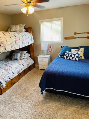 A bedroom with a bunk bed, a single bed, a nightstand, a lamp, a window with blinds, and a ceiling fan. - Lake Cumberland Hideaway #1-2 miles from Jtown Marina! Boat Parking & Fire Pit! (Jamestown)