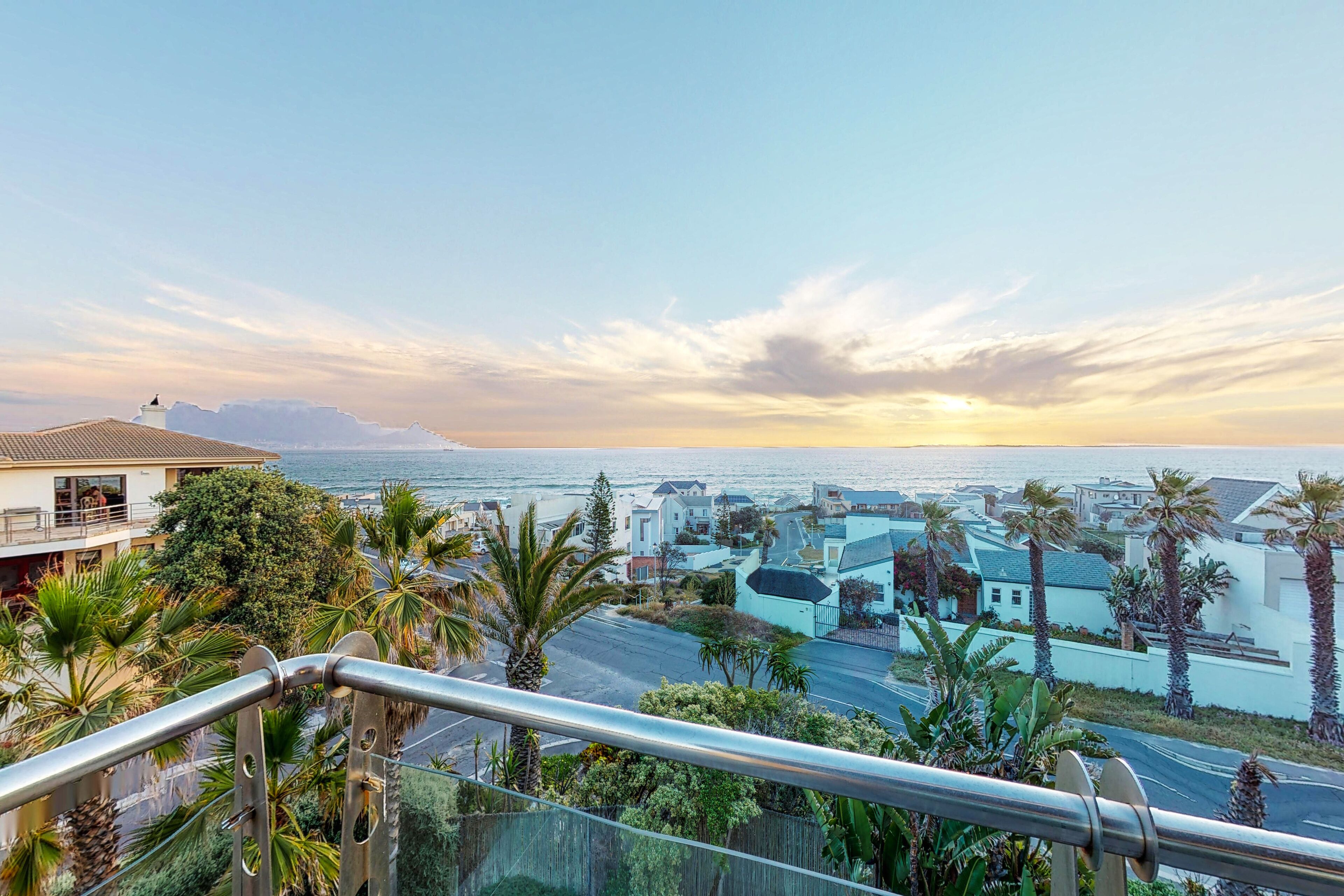 A coastal residential area with houses, palm trees, and a view of the ocean.