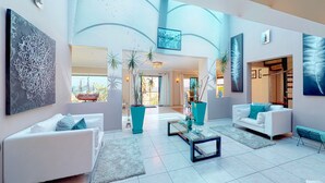 A spacious living area with a white sofa, a glass coffee table, and teal planters. - Luxury Beach Villa (Cape Town)