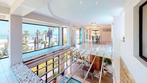 A spacious interior with a pool, large windows, and a view of the beach. - Luxury Beach Villa (Cape Town)