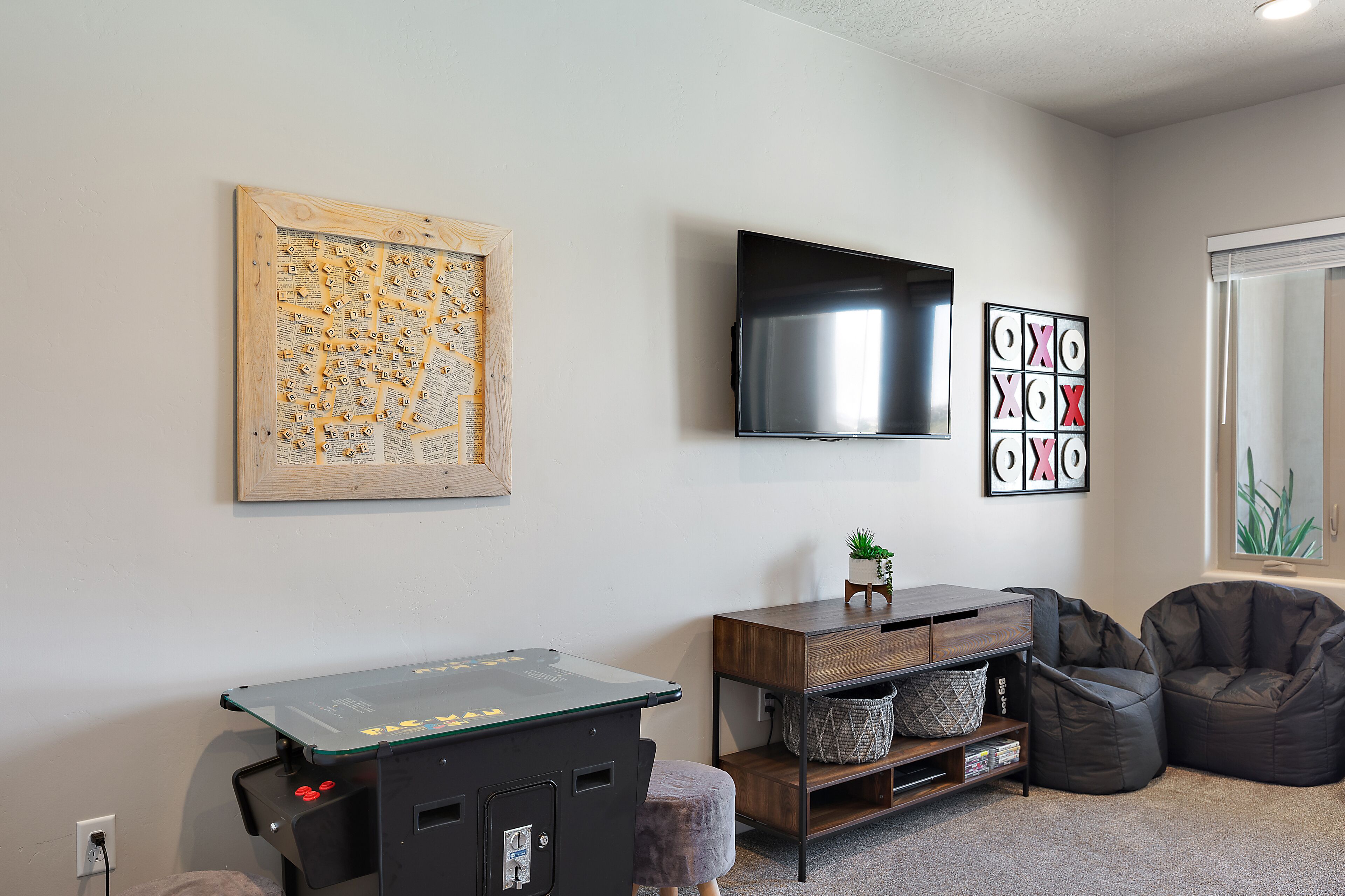 A room with a ping pong table, a flat-screen TV, a wall-mounted artwork, and a bean bag chair.
