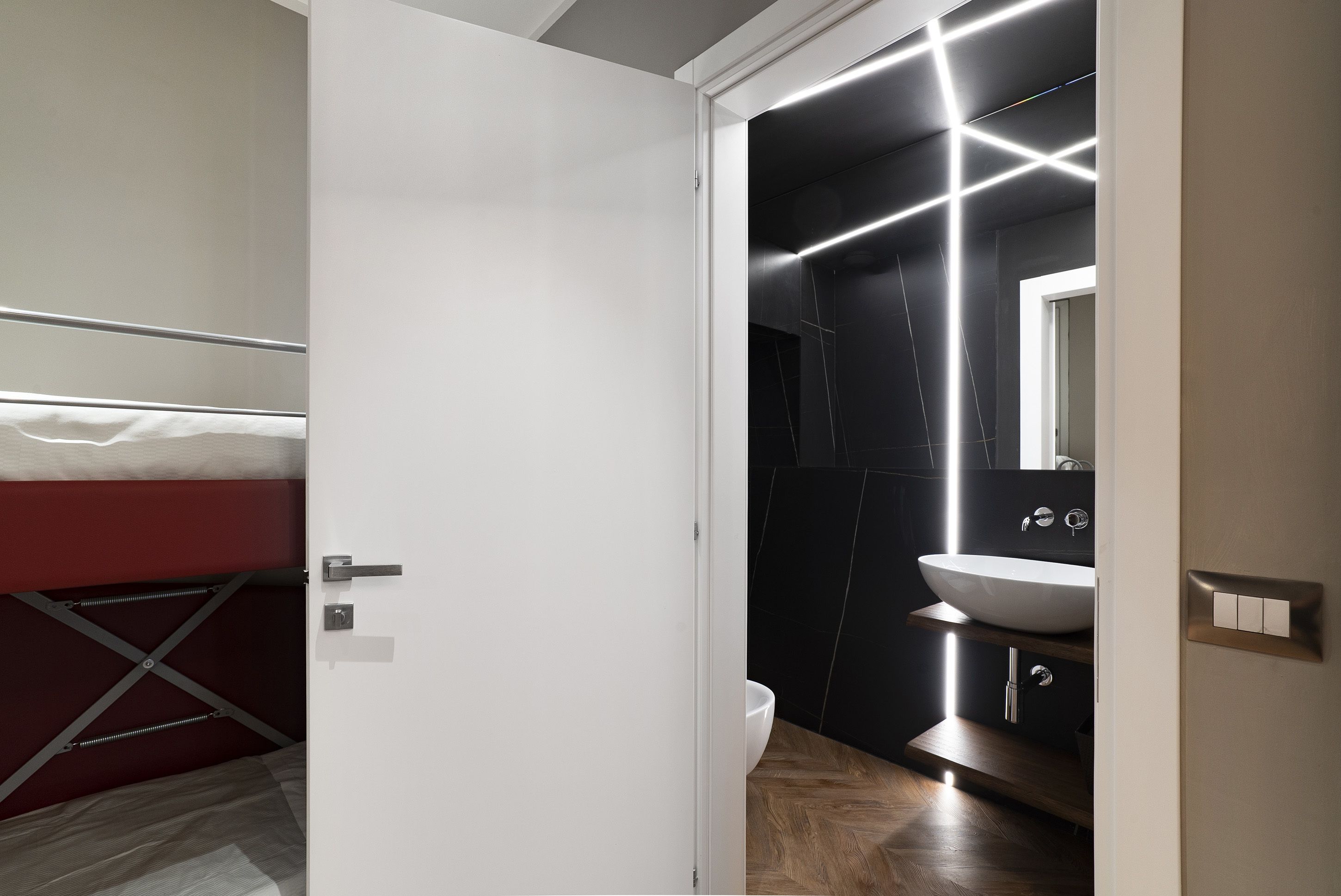 A modern bathroom with a white sink, dark tiles, and a mirror.