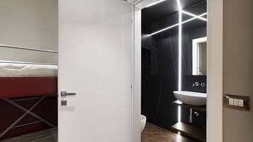 A modern bathroom with a white sink, dark tiles, and a mirror.