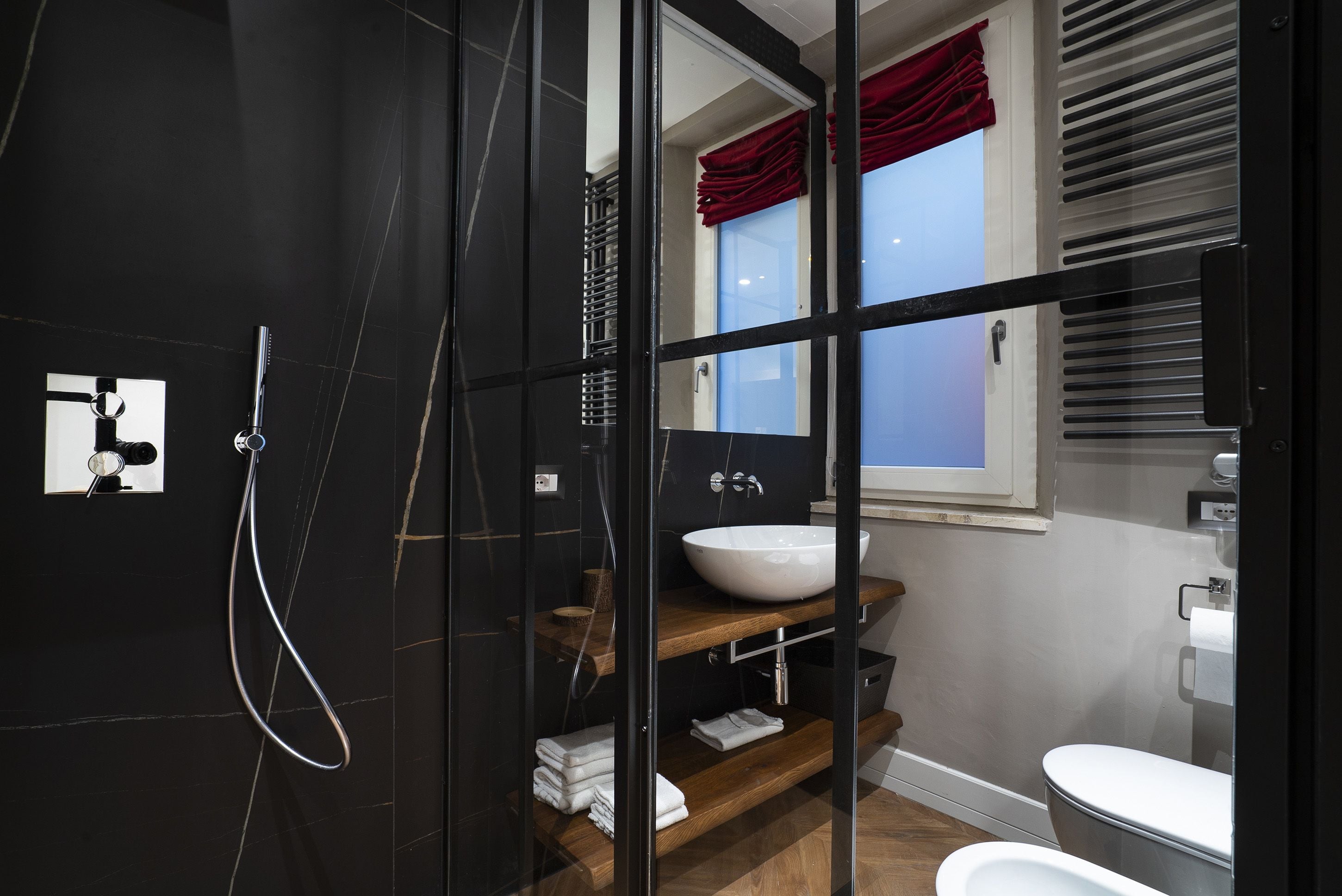 A modern bathroom with a glass shower enclosure, a wooden vanity with a white sink, and a toilet.