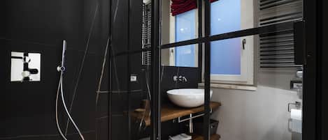 A modern bathroom with a glass shower enclosure, a wooden vanity with a white sink, and a toilet.