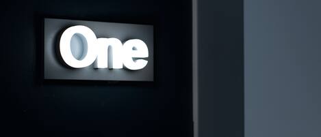 A sign with the word "One" illuminated in white against a dark background.