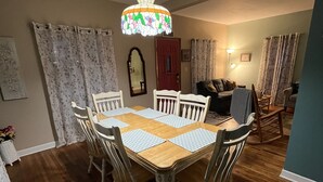 Un comedor con una mesa y sillas de madera, una araña y una puerta roja.