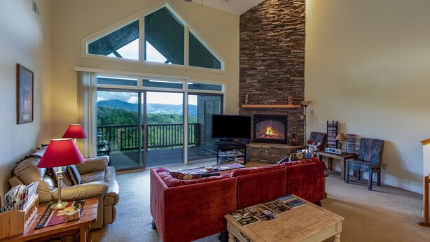 A spacious living room with a fireplace, a large window, and a balcony. - 2B Condo w/ Game Tables and Great Views! (Sugar Mountain)