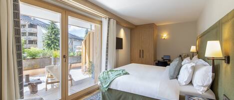 Hotelkamer met een groot bed, een houten hoofdeinde, een nachtkastje, een bureau met een lamp en uitzicht op het balkon.