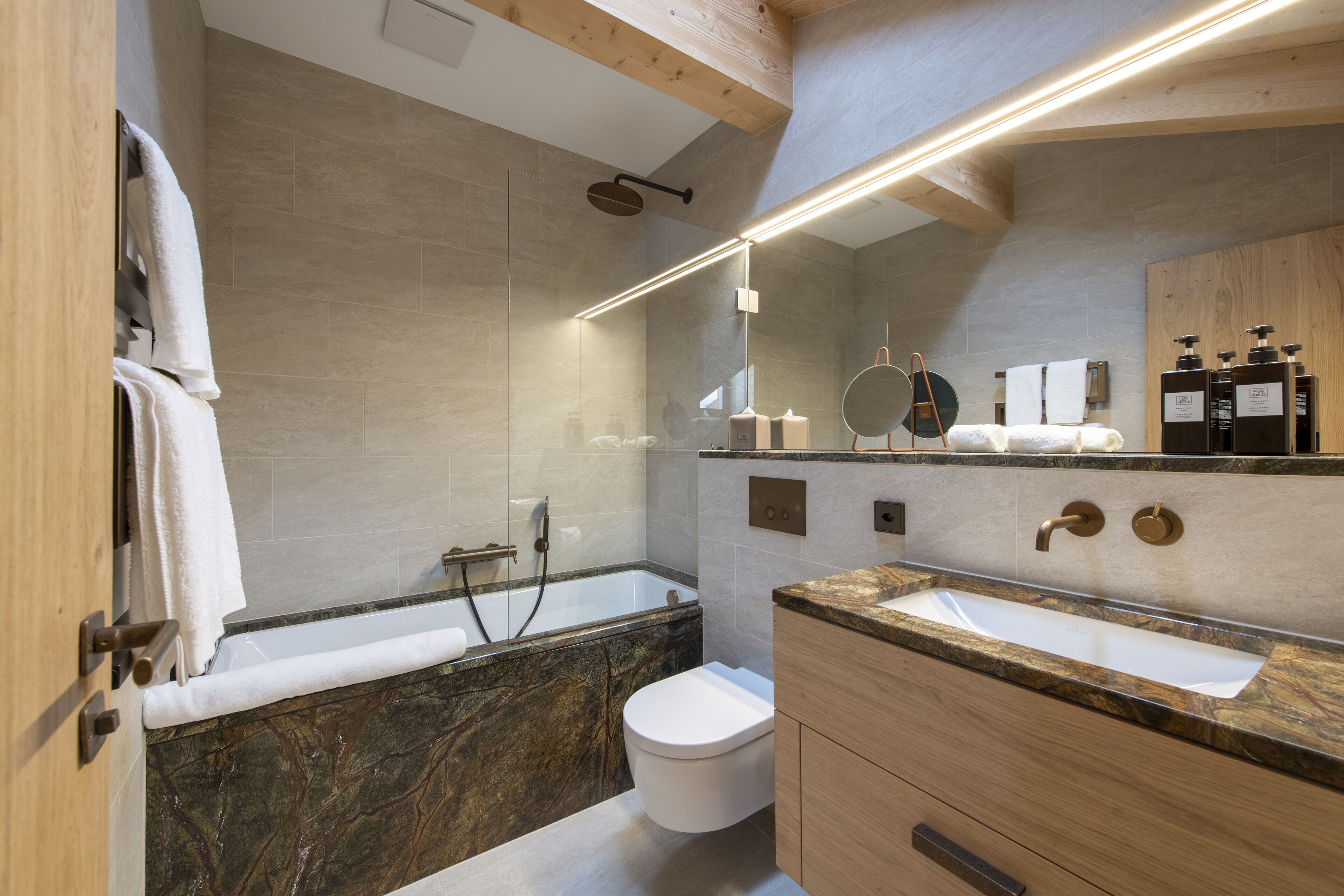 A modern bathroom with a bathtub, toilet, and vanity with a sink.