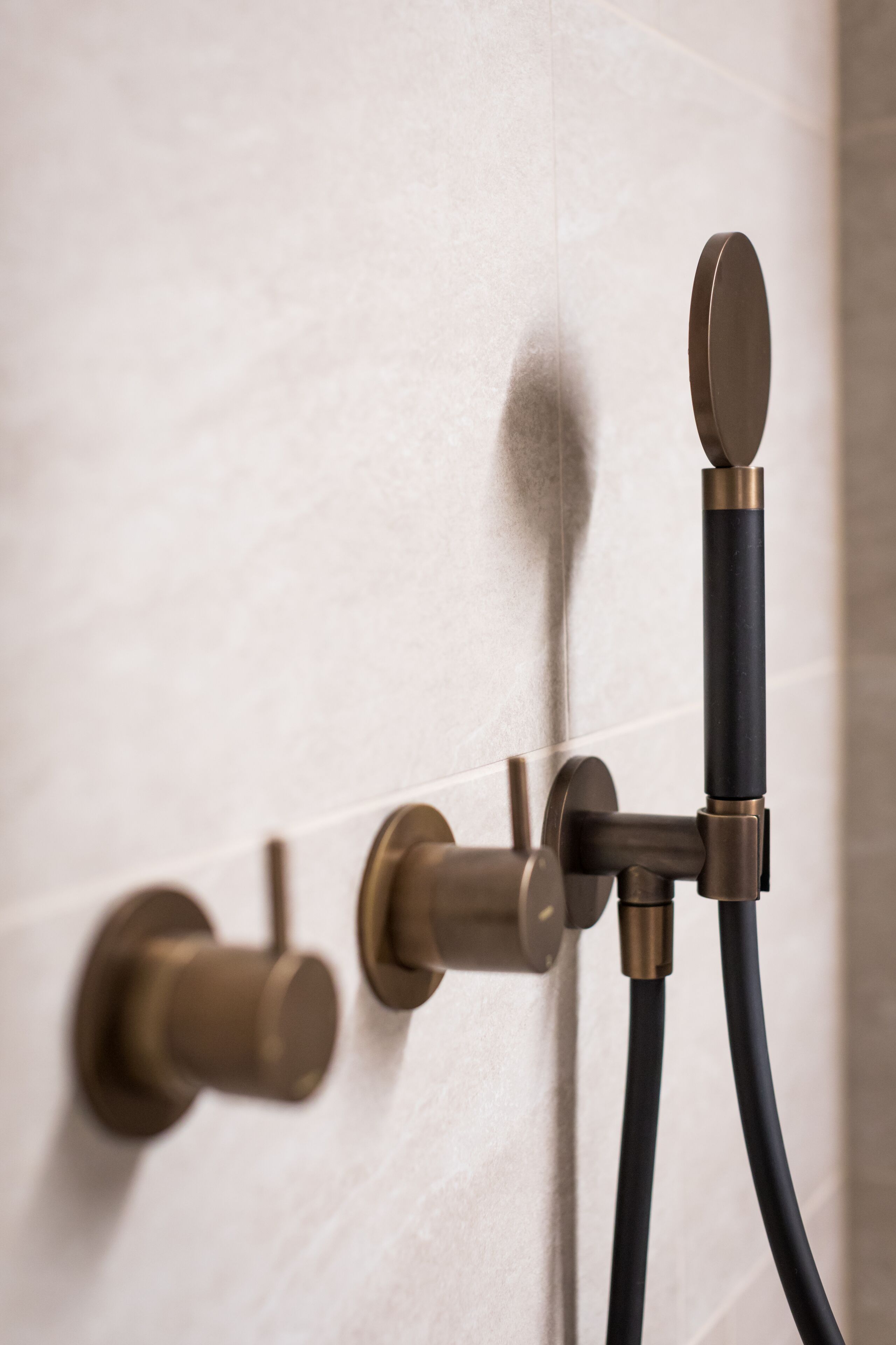 A bathroom with a modern shower system, including a handheld showerhead and a wall-mounted control valve.