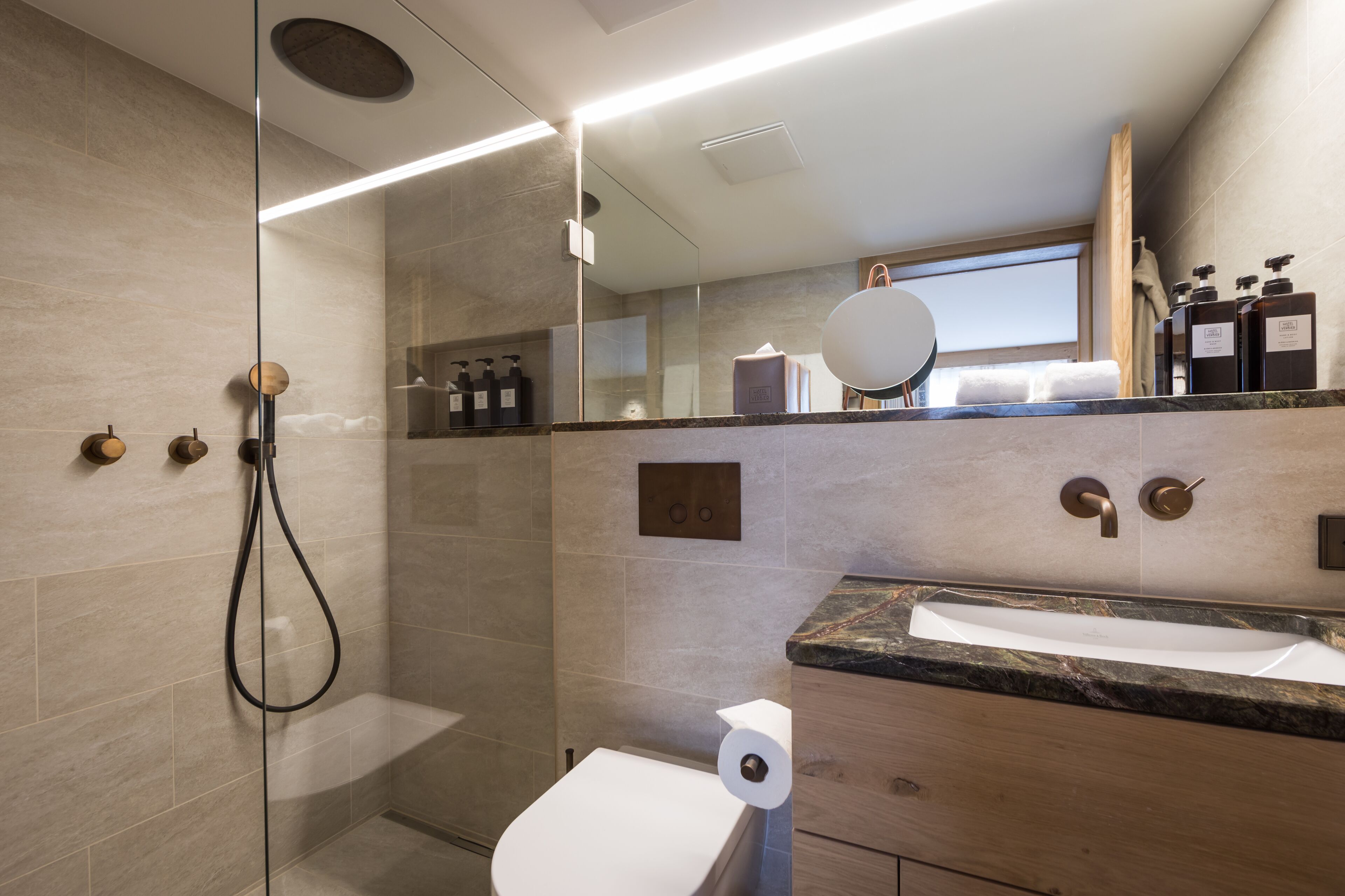 A modern bathroom with a glass-enclosed shower, a marble sink, and a wooden vanity.