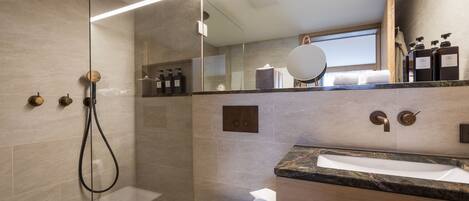 A modern bathroom with a glass-enclosed shower, a marble sink, and a wooden vanity.