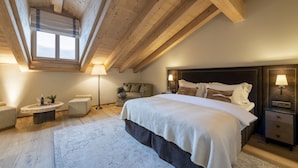 A bedroom with a large bed, a wooden ceiling, a window, a bedside table, and a nightstand. - Hôtel de Verbier SUP (Bagnes)