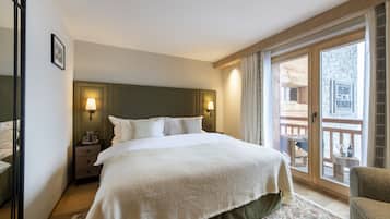 A hotel room with a large bed, two bedside lamps, a nightstand, a chair, and a balcony with a view of the city.