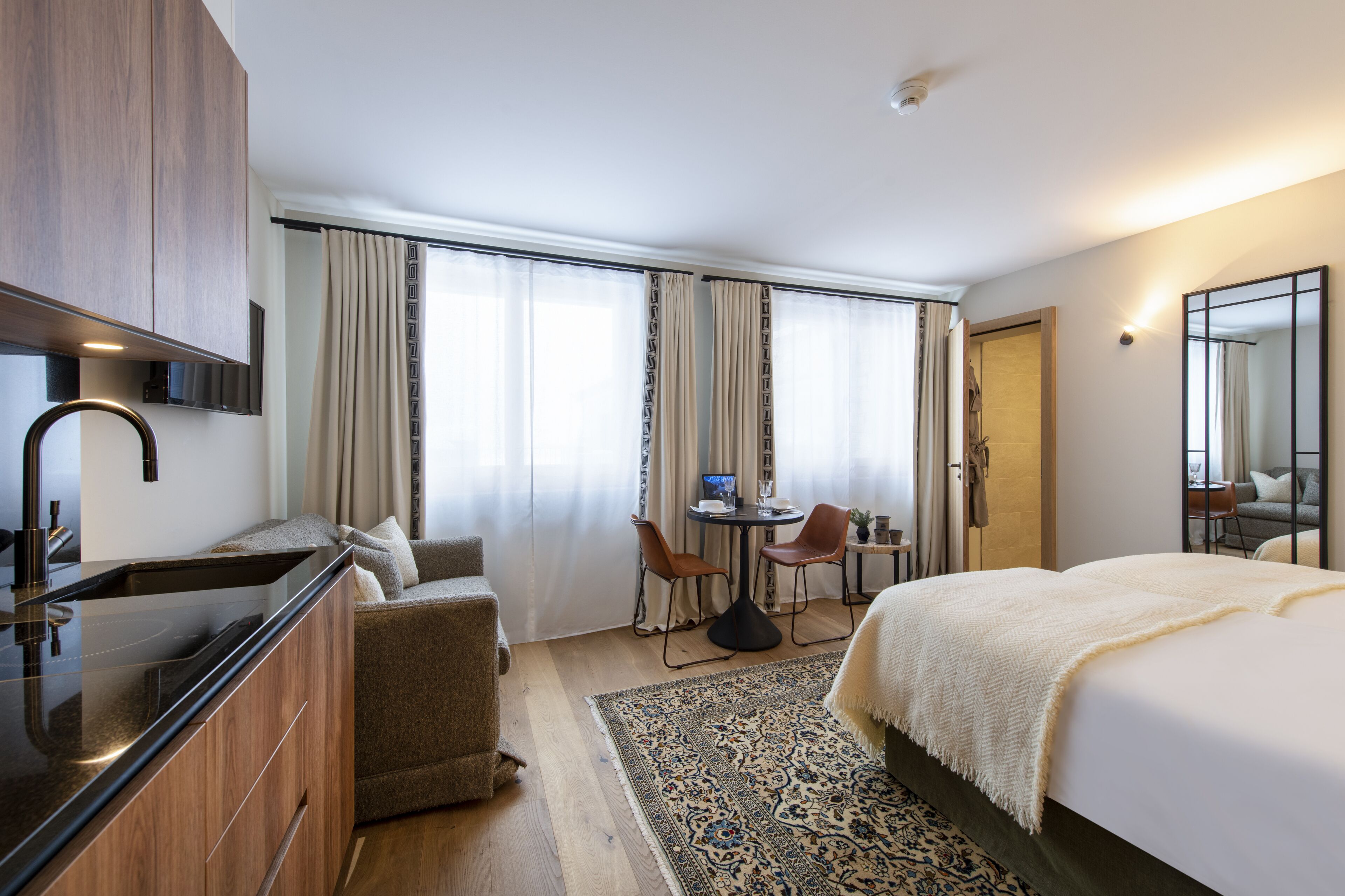 Une chambre d’hôtel moderne équipée d’un lit, d’un bureau, d’une chaise, d’un canapé, d’une télévision et d’une salle de bain.