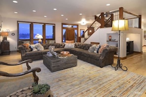 A spacious living room with a large sectional sofa, a wooden coffee table, and a staircase leading to an upper level.