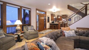 A spacious living room with a large sectional sofa, a dining area, and a kitchen.