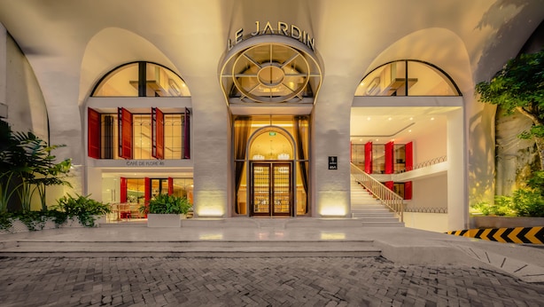 Ein Hotel Eingang mit einem imposanten Bogen, einer Treppe und einem Café namens "CAFÉ DE FLORE 46".