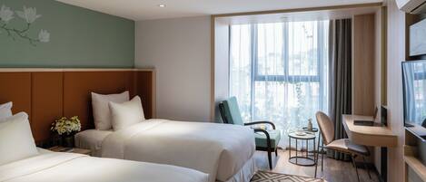 A hotel room with two beds, a desk, a chair, a small table, and a large window with curtains.