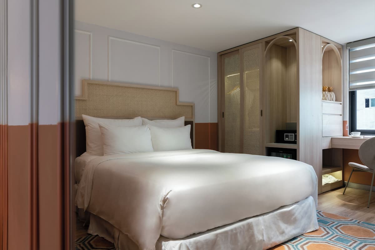 Une chambre d’hôtel avec un grand lit, un bureau et une armoire.