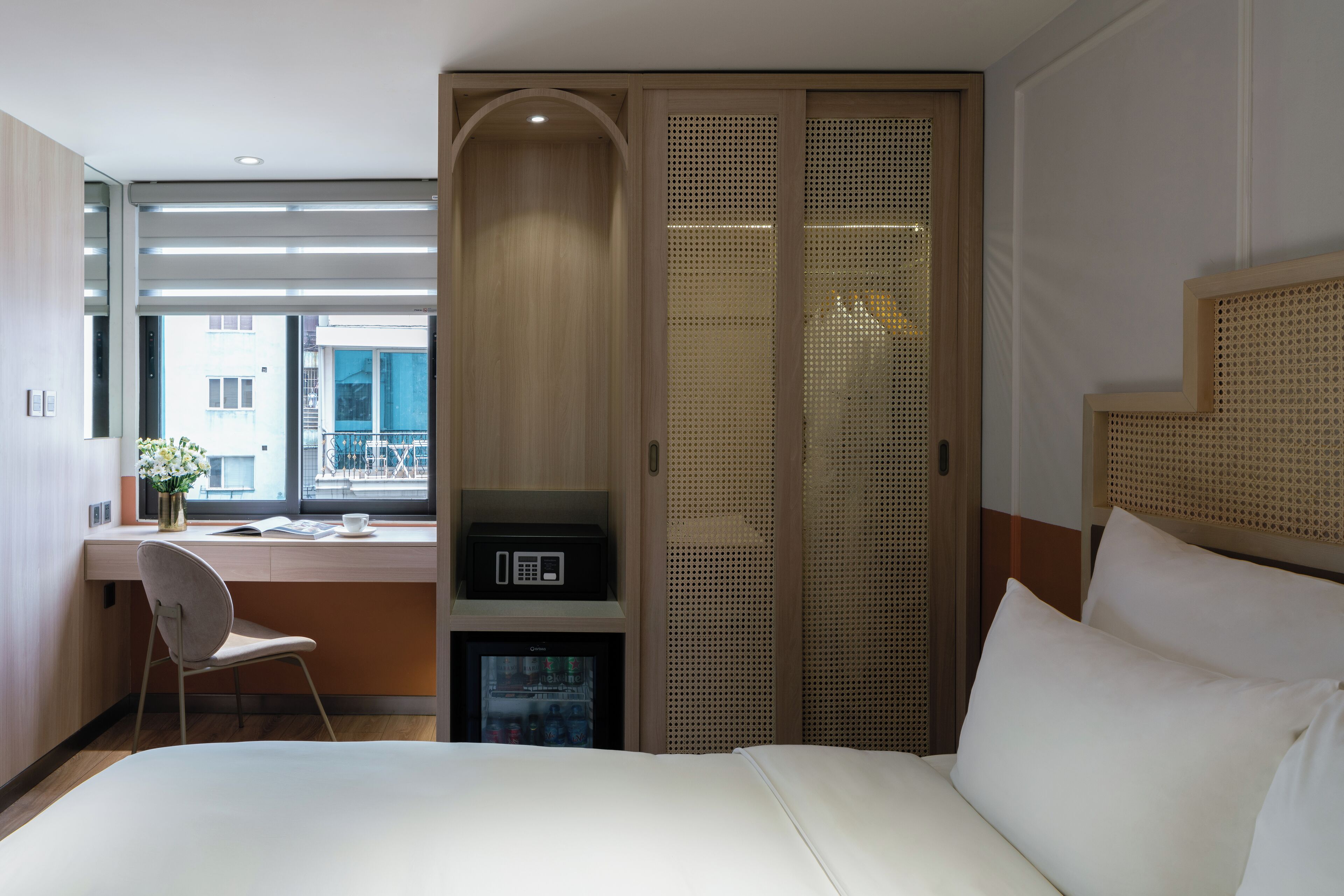 Habitación de hotel con cama, escritorio con silla, televisor pequeño y armario con espejo.