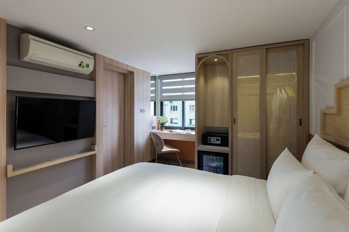 Une chambre d’hôtel avec un lit, une télévision, un bureau et une vue sur la ville.