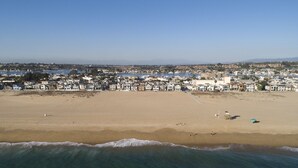 An aerial view of a beach with houses in the background and a clear sky.