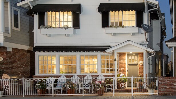 A two-story house with a balcony and a fenced front yard.