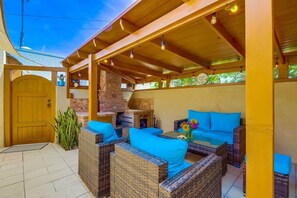 An outdoor patio with wicker furniture, a brick fireplace, and a wooden door.