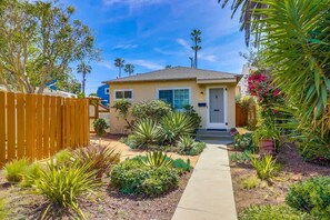 A residential house with a front yard, a wooden fence, and various plants.