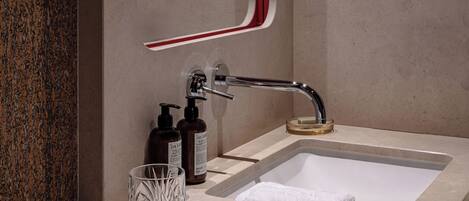 Un bagno moderno con un lavabo rettangolare, un bicchiere e due flaconi di sapone.