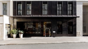 A modern building with a dark facade, large windows, and a visible entrance with a metal gate. - Experimental Marais (Paris)