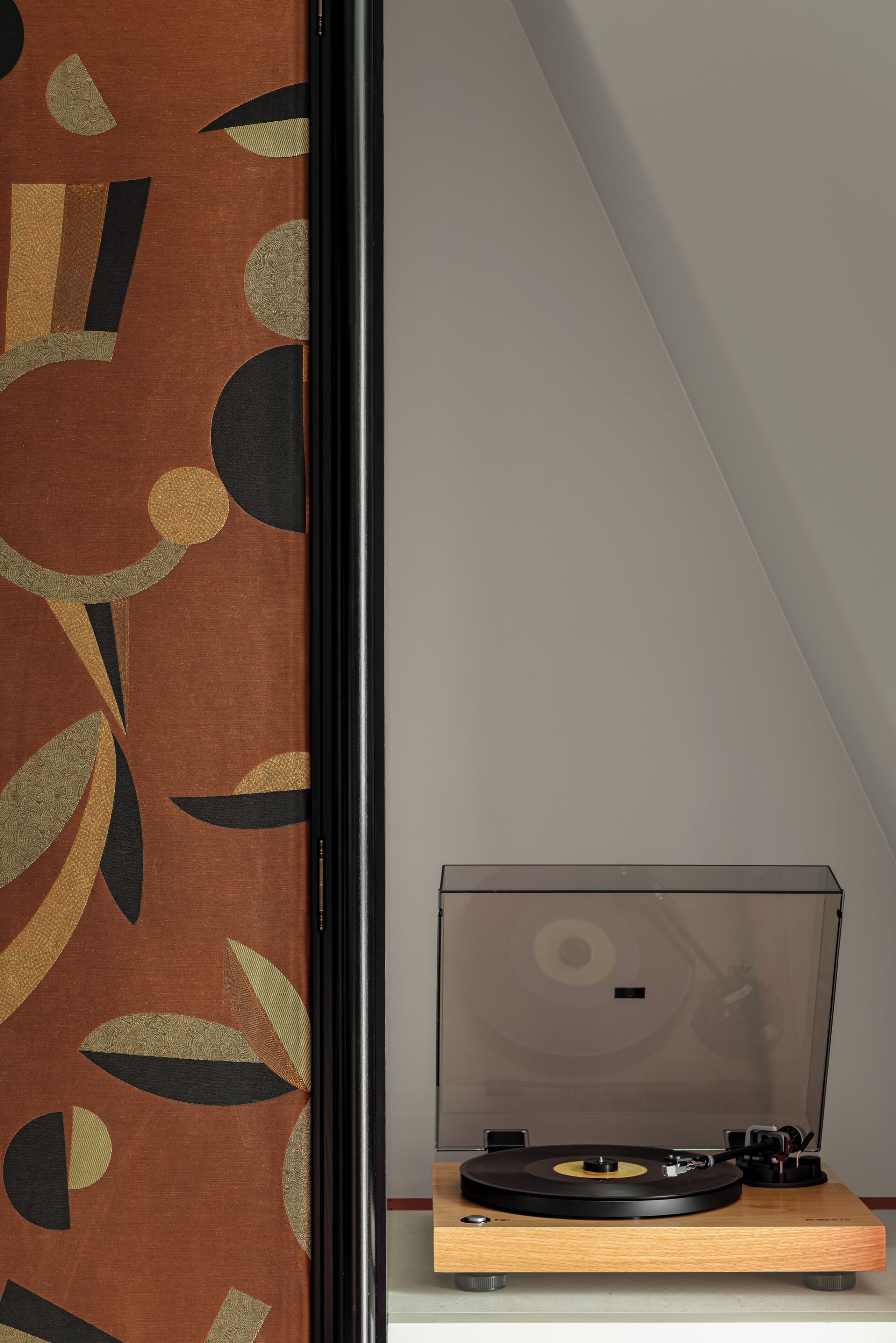 A turntable on a wooden stand in a room with a patterned wall.