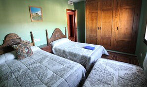 A bedroom with two beds, a wooden wardrobe, and a painting on the wall. - El Rincón de Piedra Apartamentos Rurales (Enguidanos)