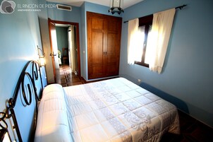 A bedroom with a bed, wooden wardrobe, and a window with curtains.