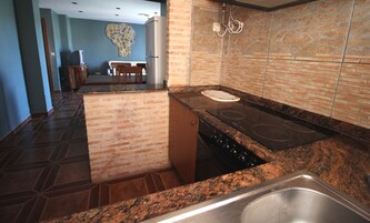 A kitchen with a granite countertop, a stainless steel sink, and a built-in stove.