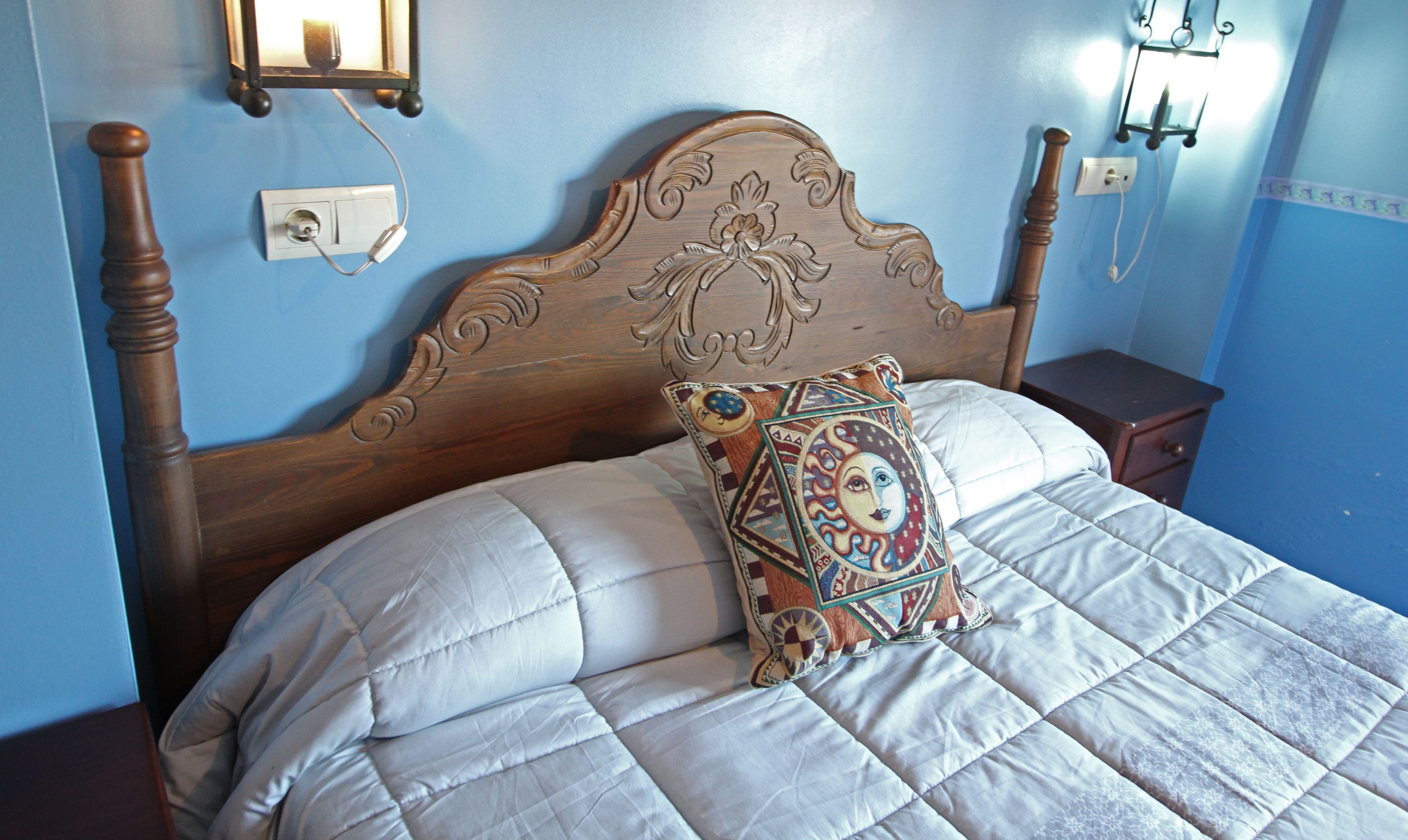 A bed with a wooden headboard, a patterned pillow, and a white quilt.